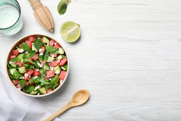 Delicious salad with watermelon, cucumber, arugula and feta cheese on white wooden table, flat lay. Space for text