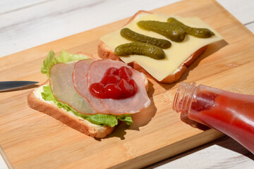 Toast with ham and a leaf of green lettuce poured with ketchup on a wooden background.