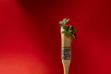 Painting brush decorated with green plants. Red background.