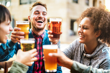 Multicultural happy friends drinking and toasting beer at brewery bar restaurant - Beverage life style concept with men and women having fun together out side - Bright warm filter with focus on guy
