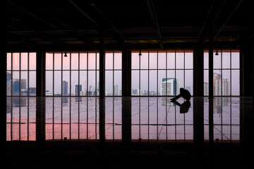 Tired or depressed businessman sitting on floor and holding hands on head alone inside the empty room of the high office building.