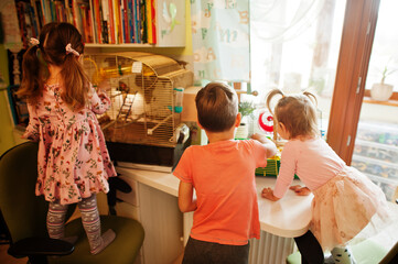 Three children holding their favorite pets on hands. Kids playing with hamster,turtle and parrots at home.