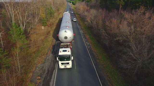 Aerial view. A powerful tractor pulls oversized cargo. A huge metal column for the chemical industry.