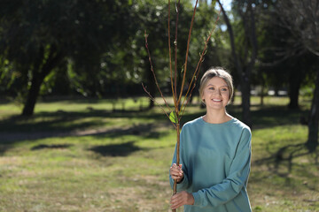 Happy woman with young tree ready for planting outdoors on sunny day