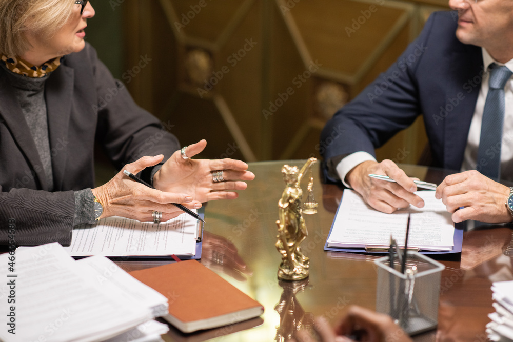 Aufkleber Two experienced lawyers in formalwear consulting about some working points while looking through juridical documents by workplace