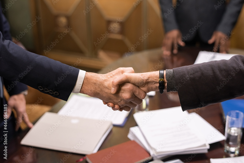Aufkleber hands of two mature successful business partners handshaking over table with signed documents after 