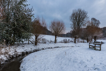 Snow nature landscapes in a Brussels park with bare trees
