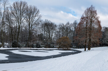Fototapeta na wymiar Snow nature landscapes in a Brussels park with bare trees 