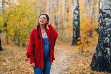 woman stands and admires the beauty of nature in the autumn forest