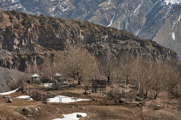 A cemetery on a hill in a mountain valley. High snow-capped mountains in the background