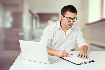 Happy mature executive manager using laptop writing notes