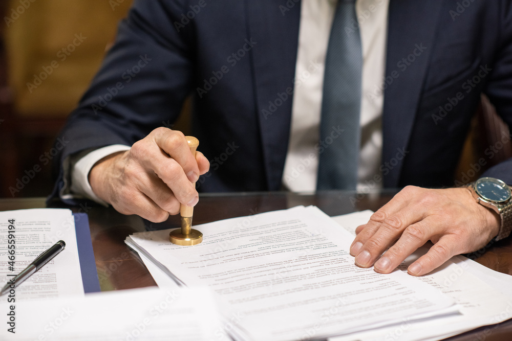 Poster hands of director in elegant suit putting stamp on approved document such as certificate, contract, 