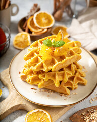 Homemade pumpkin waffles with walnuts in a plate on a culinary background close-up