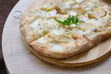 Roman round pizza five or four cheeses on a round wooden kitchen pizza board. Delicious fresh Italian pizza on a round wooden table. Selective focus