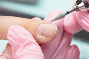 Removing the nail plate with a milling machine. Manicure process in beauty salon, cleaning of nails...