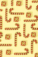 Trendy pattern with red Christmas candy canes and gift boxes on a yellow background. New Year holiday wallpaper. Flat lay.