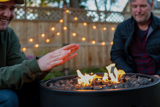 Father And Son Hanging Out Around A Backyard Fire Pit