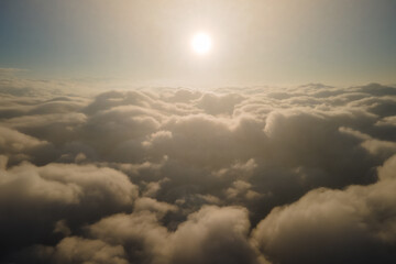 Aerial view from airplane window at high altitude of dense puffy cumulus clouds forming before rainstorm in evening