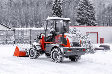 Man on red tractor with snowplow removing snow during the snowfall.  Blizzard weather conditions. Winter time street maintenance. Shallow dept of field. Blurry background. 