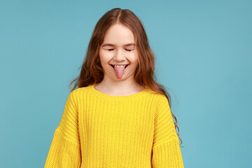 Portrait of funny playful adorable little girl showing tongue out, posing with childish expression,...