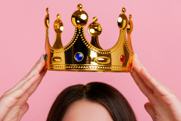 Unknown woman putting on golden crown, arrogance and privileged status, concept of self confidence...