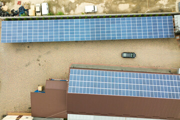 Aerial view of solar power plant with blue photovoltaic panels mounted of industrial building roof.