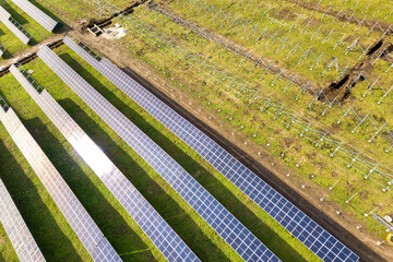 Aerial view of solar power plant under construction on green field. Assembling of electric panels for producing clean ecologic energy.