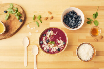 Overview of several bowls with fresh homemade vegetable smoothie and ingredients on wooden kitchen table