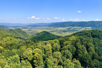 Naklejka premium Aerial view of mountain hills covered with dense green lush woods on bright summer day.