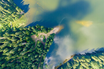 Top down aerial view of big lake with clear blue water between high mountain hills covered with...