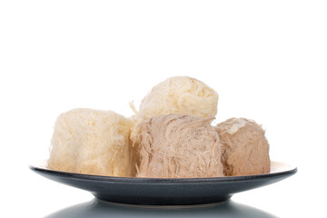 Several sweet cotton candy on a ceramic plate, close-up, isolated on white.