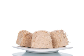 Several sweet cotton candy on a ceramic plate, close-up, isolated on white.