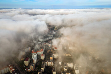 Obraz premium Top aerial view of fluffy white clouds over modern city with high rise buildings.