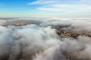 Top aerial view of fluffy white clouds over modern city with high rise buildings.