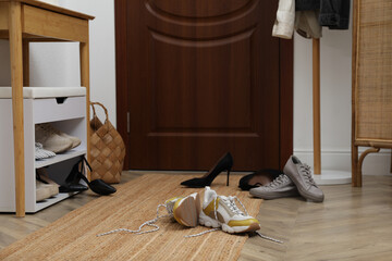Fototapeta na wymiar Different stylish shoes scattered on floor in hall