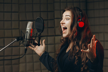 Female with microphone recording a voice for dubbing in music studio