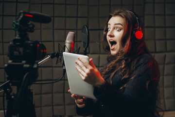 Young girl with microphone and headphones in recording studio. Recording of vocal, blogger, reading...