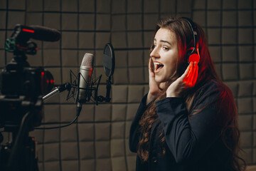 Female with microphone recording a voice for dubbing in music studio - obrazy, fototapety, plakaty