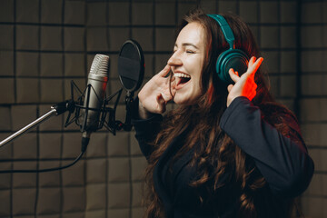 Female with microphone recording a voice for dubbing in music studio