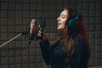 Female with microphone recording a voice for dubbing in music studio