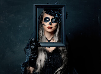 portrait of a girl in a witch costume with photo frame on a dark background