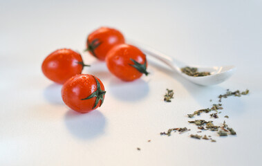 red cherry tomatoes and white spoon on a white background 