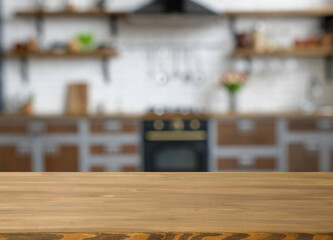 Wooden table with free space and blurred kitchen on the background.