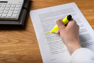 Contract terms of contract. Hand highlighting word in legal agreement, studying and reading...