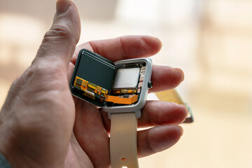 smartwatch broken by a fall or blow showing the electronic circuit inside held in one hand