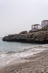 Two cabanas at Dhermi Beach, in Albania, sit on top of an outstretched rock that extends from the...