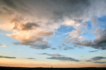 Naklejka na ściany i meble Bright landscape of dark clouds on yellow sunset sky in evening.