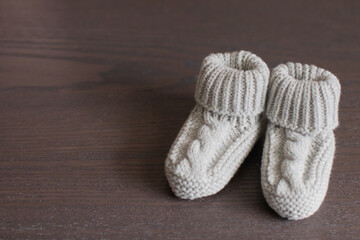 Fototapeta na wymiar Gray Knitted Baby Socks (booties) on brown background