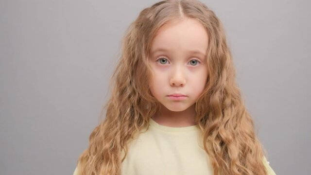 The little girl is angry. Picture taken in the studio on a gray background. Super slow motion.