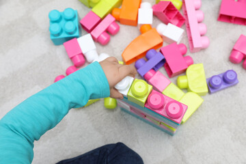 Naklejka premium Top view of little child playing with building blocks on carpet, closeup